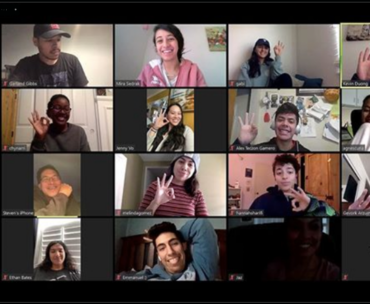 A Zoom call gallery view of students smiling and holding up 3 fingers.