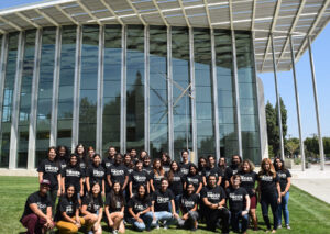 A group of students wearing BUILD PODER shirts standing in front of a building