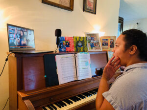 Pauline Tamale, a graduate music major in vocal performance, sits a piano to works with CSUN Opera Music Director Mercedes Juan Musotto (via a computer screen) to record a vocal for CSUN's upcoming animated opera.