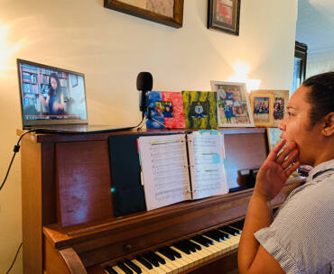 Pauline Tamale, a graduate music major in vocal performance, sits a piano to works with CSUN Opera Music Director Mercedes Juan Musotto (via a computer screen) to record a vocal for CSUN's upcoming animated opera.