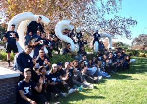 Trainers from 3WINS Fitness pose in front of a CSUN sculpture