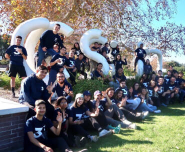 Trainers from 3WINS Fitness pose in front of a CSUN sculpture