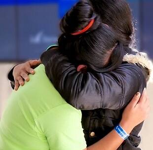 A woman in a coat hugs her 16-year-old daughter tight after a two-month separation while in the custody of the U.S. federal government.