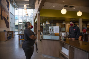 In a mask, Tracey Spann speaks to a worker at the counter of the community center.