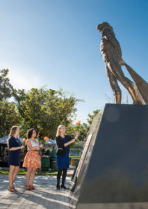 President Harrison and two others hold roses by a statue of Matty the Matador