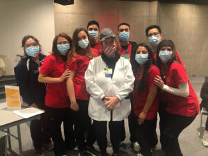 A group of CSUN students in masks and scrubs take a group photo after volunteering to assist with COVID-19 vaccinations.