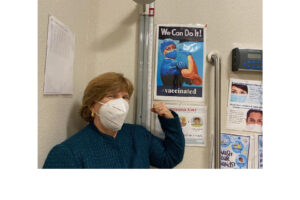 CSUN alumna Terri Stratton, ’78 (Health Science), MPH ’85 (Public Health), the chief executive officer of El Dorado Community Health Centers, poses with a COVID-19 vaccine poster.