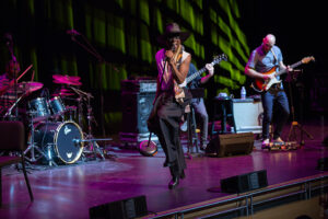 Billy Porter in a rock pose with the mic stand on stage at The Soraya.