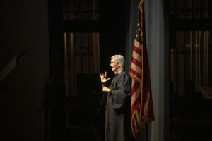 An American Sign Language interpreter in front of a United States flag.