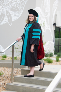A graduating student snaps a photo on campus.