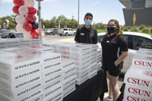 Two people stand behind stacks of Grad Boxes.