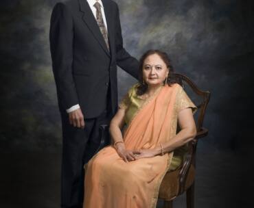 Studio portrait of Drs. Jasvant Modi and Meera Modi. Javant Modi is standing beside his wife Meera Modi who is seated.