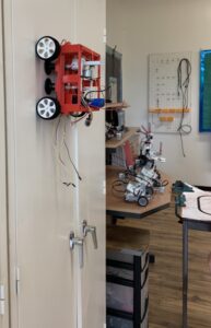 Small four-wheeled red robot on a vertical surface