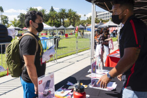 Student speaks with a person over a table covered with flyers and signs.