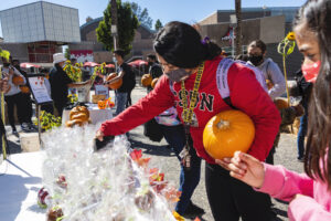 Student holding pumpkin picks out a candy apple.