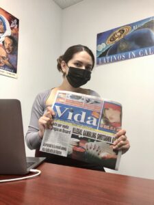 Daniela Torres is holding a newspaper that says "Vida" on the front.