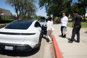 Three people stand by white car.