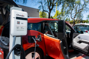 White stand that says "Chargie" with charger connected to red car.