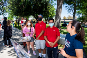 People stand on sidewalk waiting to test drive vehicles