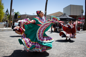 Dancer in brilliant green dress with white and pink trim swirls skirt.