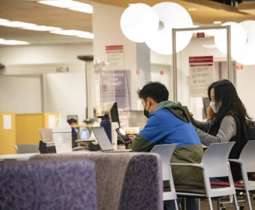Students sit at a library table studying