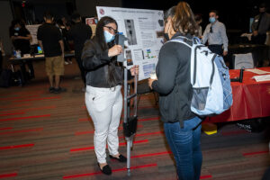 Two women stand, one holding a crutch.