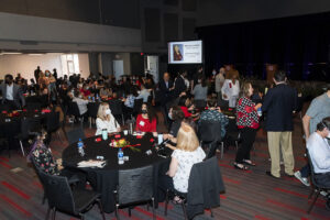 Attendees sitting at tables and standing talking to one another