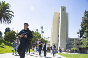 Students walk on pathway with Sierra Clock and tower in the background.