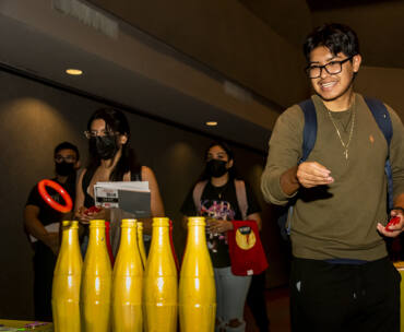 Student tosses small red rings into yellow bottles.