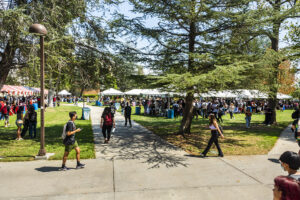 White tent canopies in background with masses of students around them.