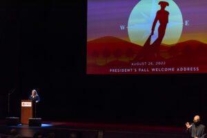 Erika D. Beck stands on stage behind podium at The Soraya with video screen showing CSUN's Matador symbol behind her.
