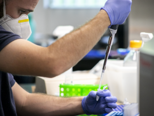 Scientist holding large syringe to be put into smaller sample sizes.