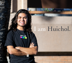 Portrait of Ethan Molina outside leaning about a tree with his arms crossed.