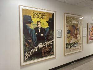 An image captured of two movie posters. One is for 'Bas les Masques,' a Humphrey Bogart Film and one is a poster for 'Une Place Au Soleil,' an Elizabeth Taylor film.