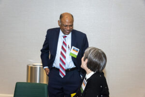 Chandra Subramaniam, dean of the David Nazarian College of Business and Economics, stands up, speaking to a woman who is seated at a table.