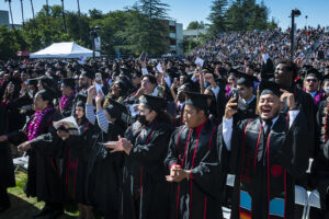 Graduates in caps and gowns cheer