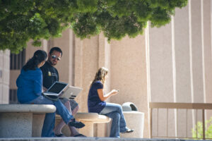 Student sits in front of University Library using her phone.