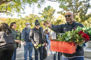 Cedric Hackett stands with basket of roses with students behind him.