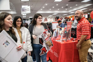 Students stop by a table to grab free pens during GradFest 2023