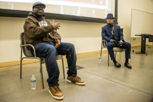 Jayquan interviews Melle Mel. They are both seated in chairs near each other.