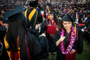 Students in caps and gowns line up with fists out for fist bumps