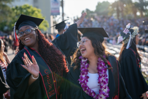 Two smiling graduates in caps and gowns
