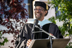William Watkins, dean of students and vice president for Student Affairs, stands at a podium and speaks into a microphone.