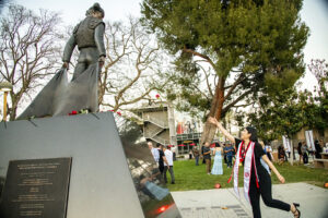 A graduate throws a red rose up toward the Matador Statue.