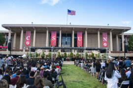 a wide shot a of the crowd and stage at a college graduation ceremony.