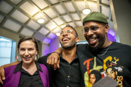 Three CSUN alumni stand with their arms around each other, laughing, at the CSUN Pride Center 10th anniversary gala.