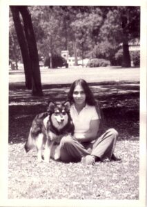 Teenage Andi Ostrowe sits on the grass with her dog beside her