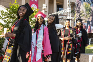 A line of women in caps and gowns smile for the camera