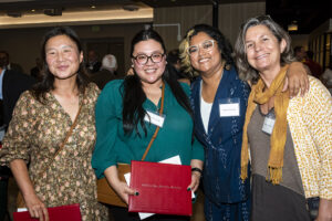 Four women stand together smiling at the camera.