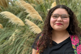 CSUN student Emily Gomez stands in front of plants and identifies as Ojibwe and Guatemalan.